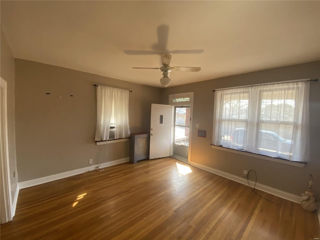 interior space featuring ceiling fan, baseboards, and wood finished floors