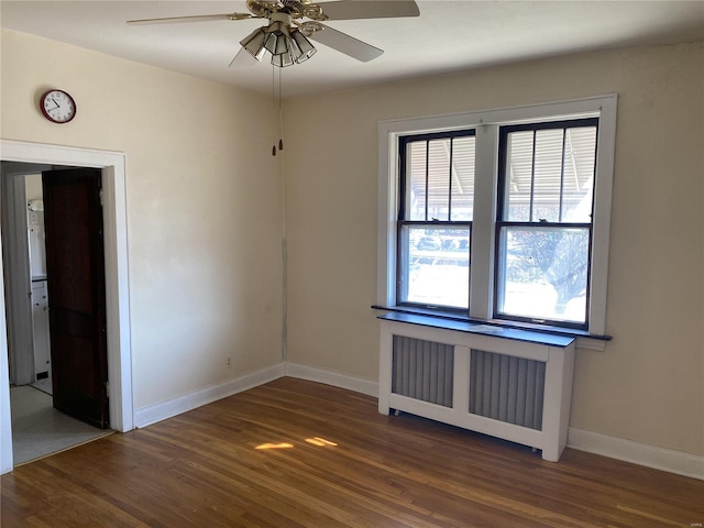 empty room with baseboards, wood finished floors, a ceiling fan, and radiator