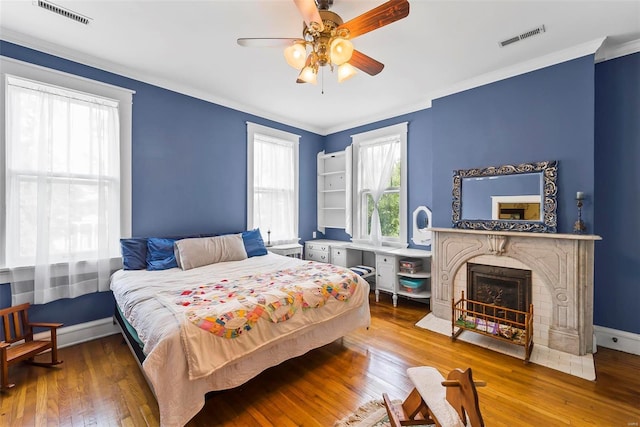 bedroom featuring a fireplace with flush hearth, baseboards, visible vents, and hardwood / wood-style floors