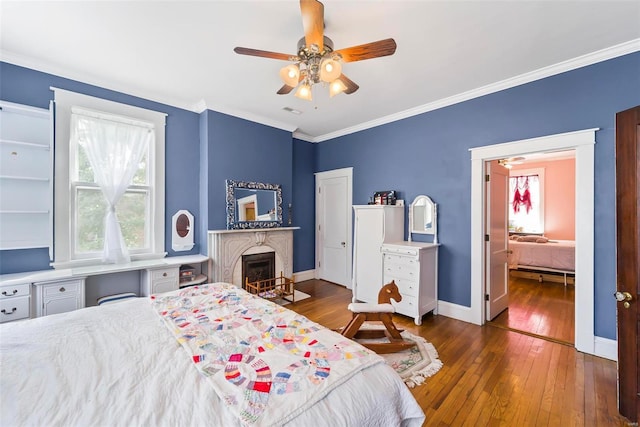 bedroom with visible vents, baseboards, hardwood / wood-style flooring, a fireplace with flush hearth, and crown molding