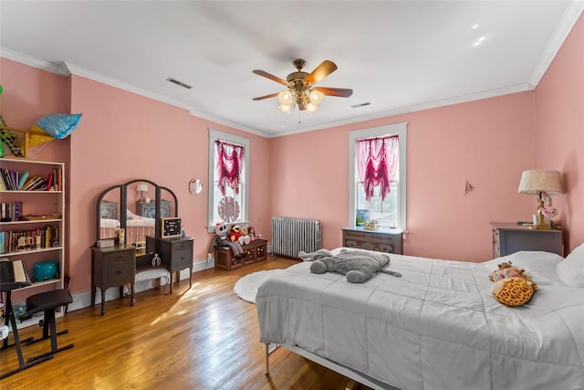 bedroom with ornamental molding, visible vents, radiator heating unit, and wood finished floors