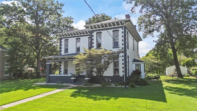 italianate home featuring a front lawn, a chimney, and fence