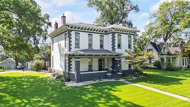 view of front of property with covered porch, a front lawn, and a chimney