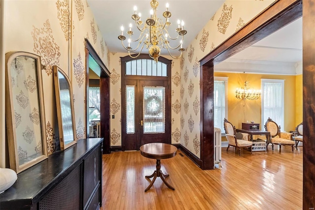 entrance foyer featuring a chandelier, baseboards, light wood finished floors, and wallpapered walls