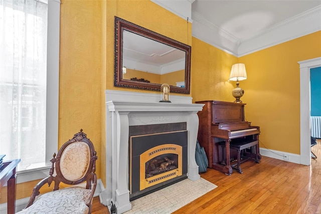 living area featuring a fireplace with flush hearth, plenty of natural light, ornamental molding, and wood finished floors