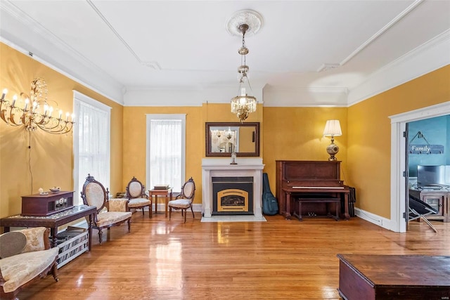 sitting room with crown molding, a notable chandelier, a fireplace with flush hearth, wood finished floors, and baseboards