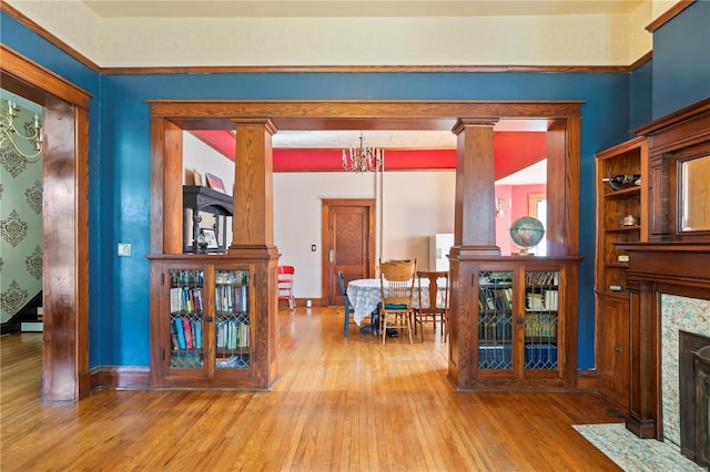 interior space featuring baseboards, hardwood / wood-style floors, a high end fireplace, and ornate columns