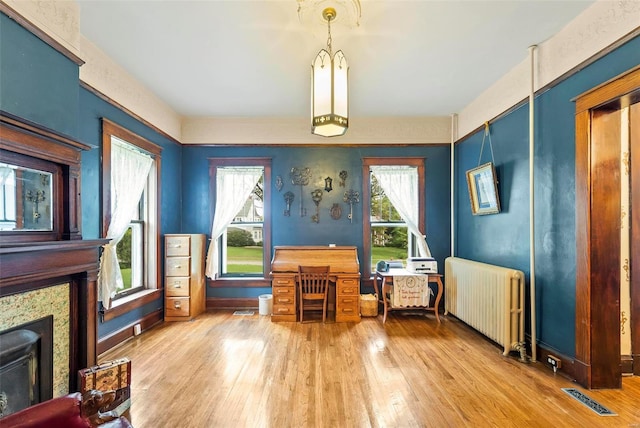 sitting room with radiator, wood-type flooring, a fireplace, and visible vents