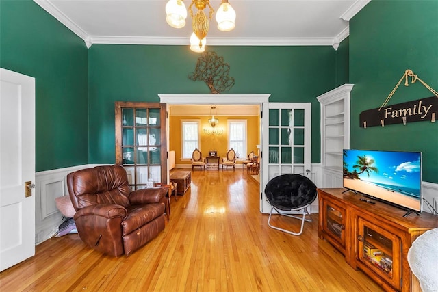 living room with ornamental molding, wood finished floors, and a notable chandelier