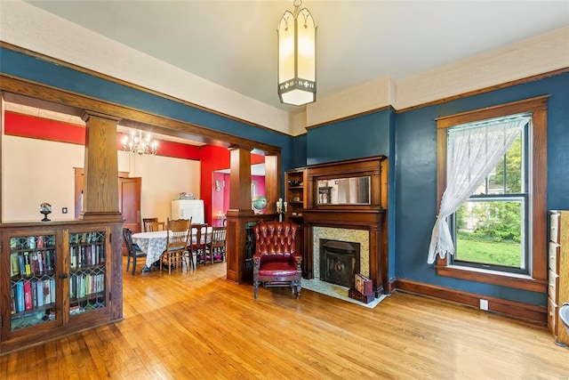 sitting room featuring ornate columns, a fireplace with flush hearth, and hardwood / wood-style flooring