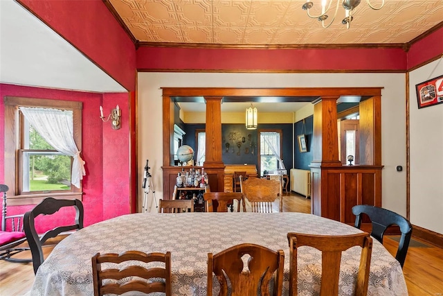 dining room featuring decorative columns, a wealth of natural light, wood finished floors, and an ornate ceiling