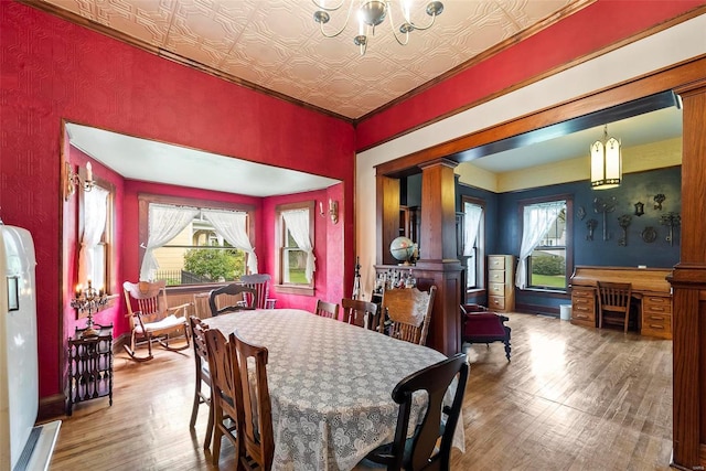 dining room featuring an ornate ceiling, a wealth of natural light, ornate columns, and wood finished floors