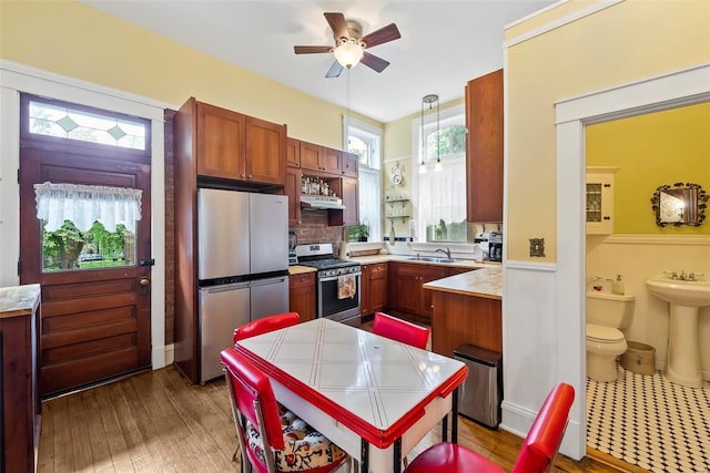 kitchen with under cabinet range hood, stainless steel appliances, a sink, and light countertops