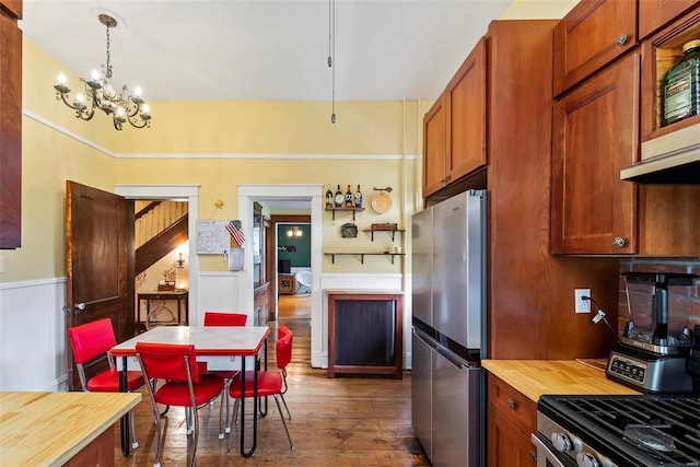 kitchen featuring wainscoting, butcher block countertops, dark wood-type flooring, freestanding refrigerator, and a chandelier