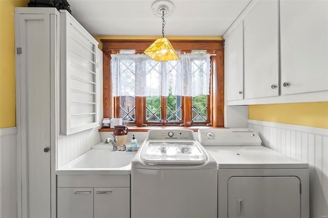 laundry room with cabinet space, a wainscoted wall, a sink, and washing machine and clothes dryer