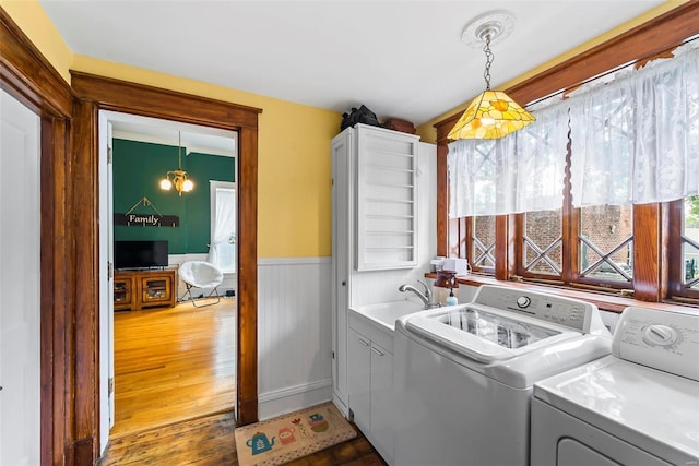 laundry room with laundry area, a wainscoted wall, wood finished floors, washer and dryer, and a sink