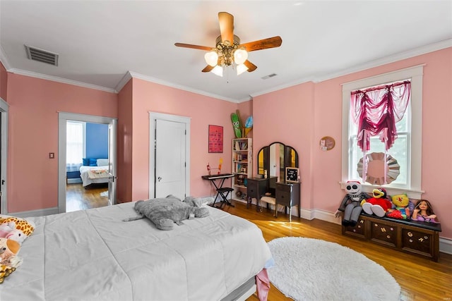 bedroom with light wood finished floors, baseboards, visible vents, and crown molding