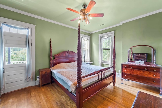 bedroom with ornamental molding, multiple windows, and hardwood / wood-style flooring