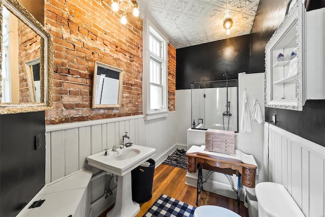 full bathroom featuring a shower with shower door, an ornate ceiling, wood finished floors, and wainscoting