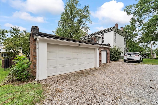 view of side of home featuring a garage, brick siding, fence, stucco siding, and a chimney