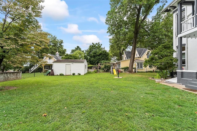 view of yard featuring a storage unit, an outdoor structure, and fence