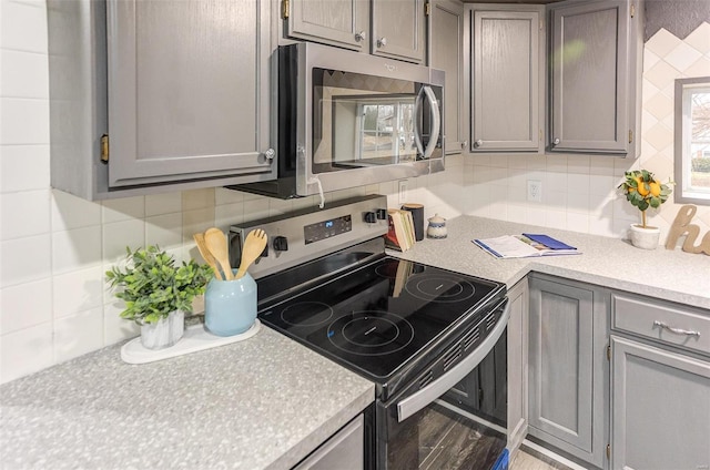 kitchen with stainless steel appliances, gray cabinets, light countertops, and decorative backsplash