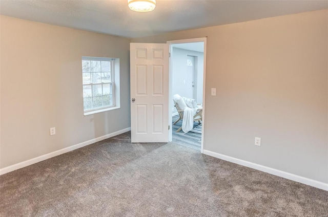 empty room featuring carpet flooring and baseboards