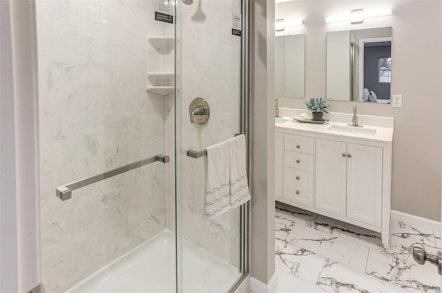 full bathroom with double vanity, a stall shower, baseboards, marble finish floor, and a sink