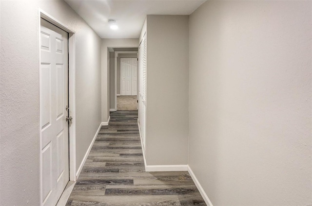 corridor featuring wood finished floors and baseboards