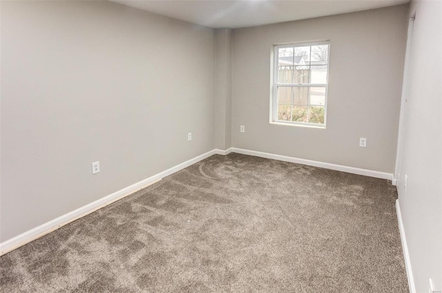 empty room with dark carpet and baseboards