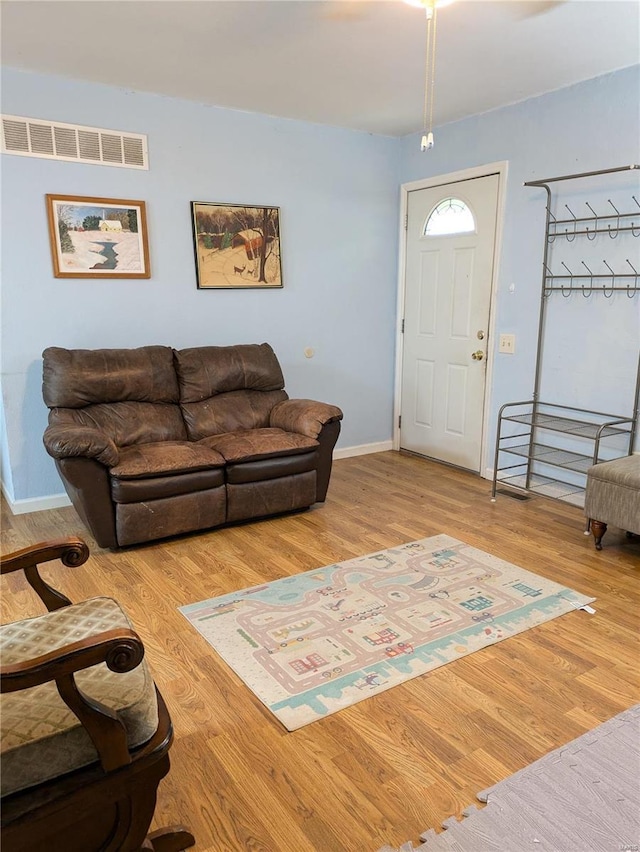 living room featuring wood finished floors, visible vents, and baseboards