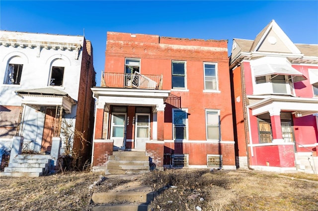 view of front of home featuring a balcony and brick siding