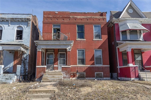 view of front of home with brick siding, central AC unit, and a balcony