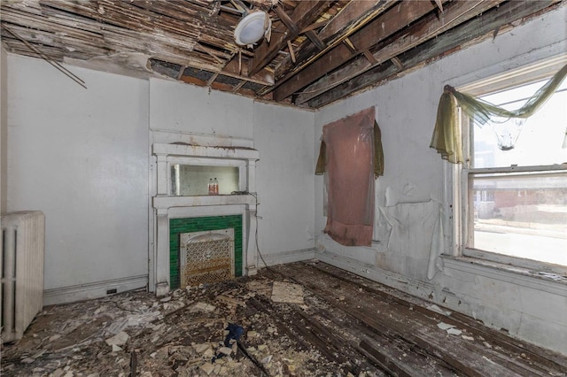 unfurnished living room featuring a fireplace and radiator heating unit