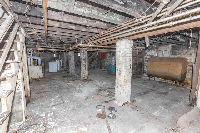 unfinished below grade area featuring heating fuel, stairway, and washer / dryer