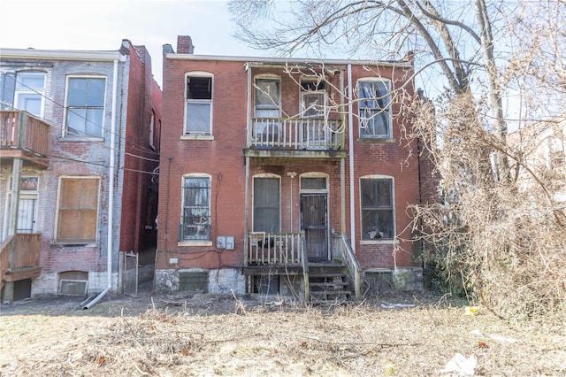 multi unit property featuring brick siding, a chimney, and a balcony