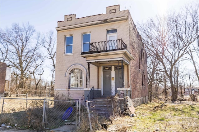 view of front facade with a balcony, a fenced front yard, and brick siding