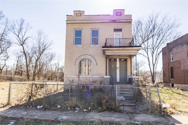 view of front of home with a balcony, a fenced front yard, a gate, and brick siding