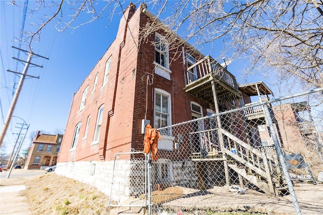 view of side of property featuring brick siding, fence, a chimney, and stairs