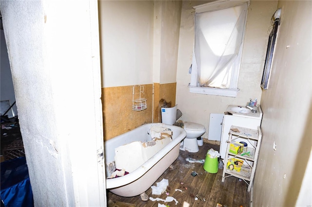 bathroom featuring wood finished floors, toilet, and a tub