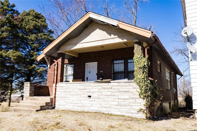 view of front of home featuring brick siding and a porch