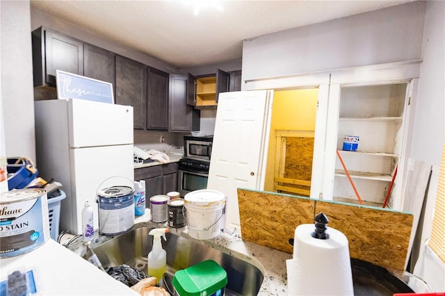 kitchen featuring wall oven, dark brown cabinets, freestanding refrigerator, open shelves, and stainless steel microwave