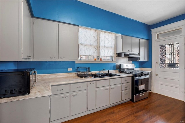 kitchen featuring stainless steel range with gas stovetop, light countertops, under cabinet range hood, black microwave, and a sink