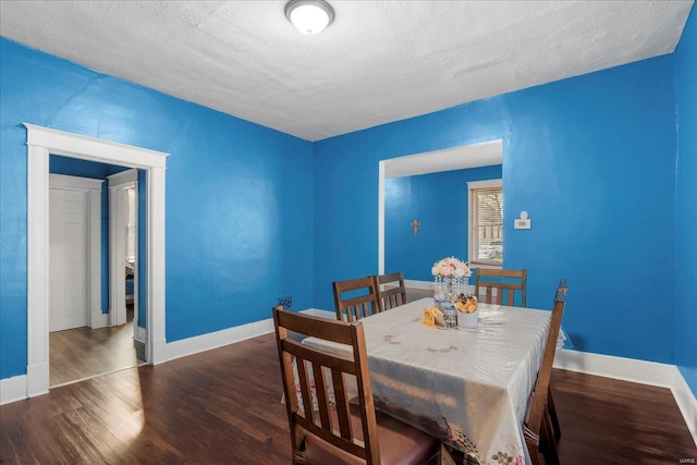 dining space featuring a textured ceiling, baseboards, and wood finished floors