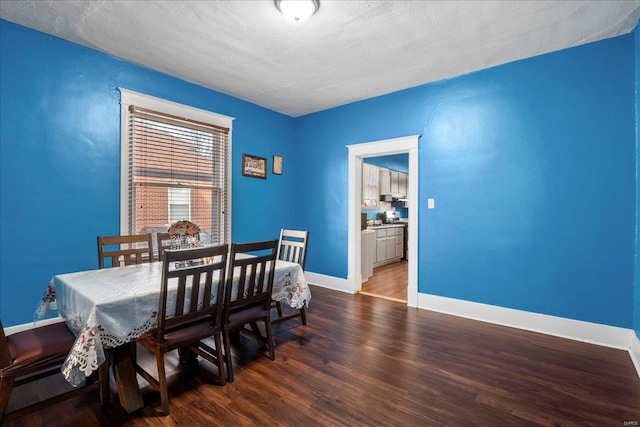 dining room with a textured ceiling, wood finished floors, and baseboards