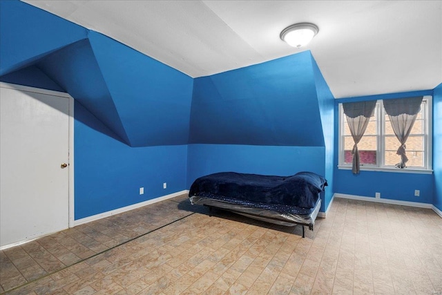 bedroom with lofted ceiling and baseboards