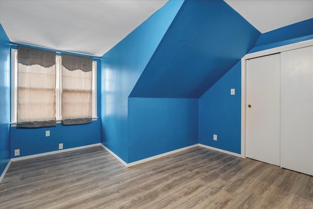 bonus room with lofted ceiling, baseboards, and wood finished floors