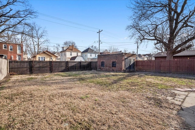 view of yard with a fenced backyard, a residential view, and an outbuilding