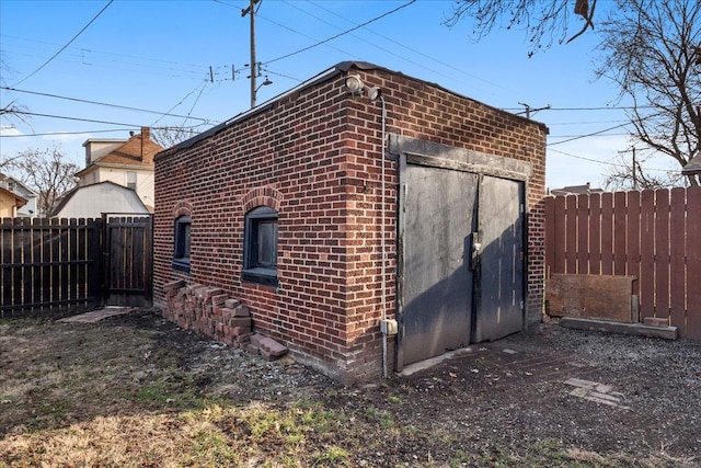 view of property exterior with a fenced backyard, an outdoor structure, and brick siding