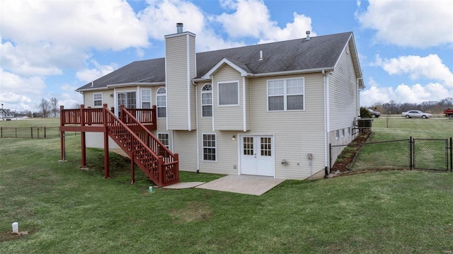 rear view of property with a gate, a yard, stairway, and fence